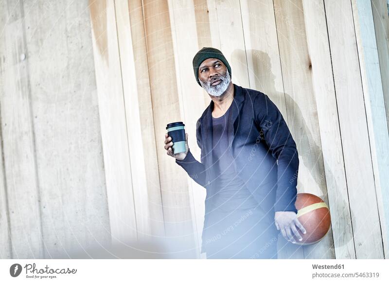 Mature businessman with takeaway coffee and basketball at wooden wall Basketball Businessman Business man Businessmen Business men wooden walls Coffee sport