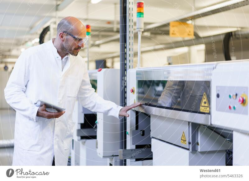 Mature male technician holding digital tablet examining machinery at factory color image colour image indoors indoor shot indoor shots interior interior view