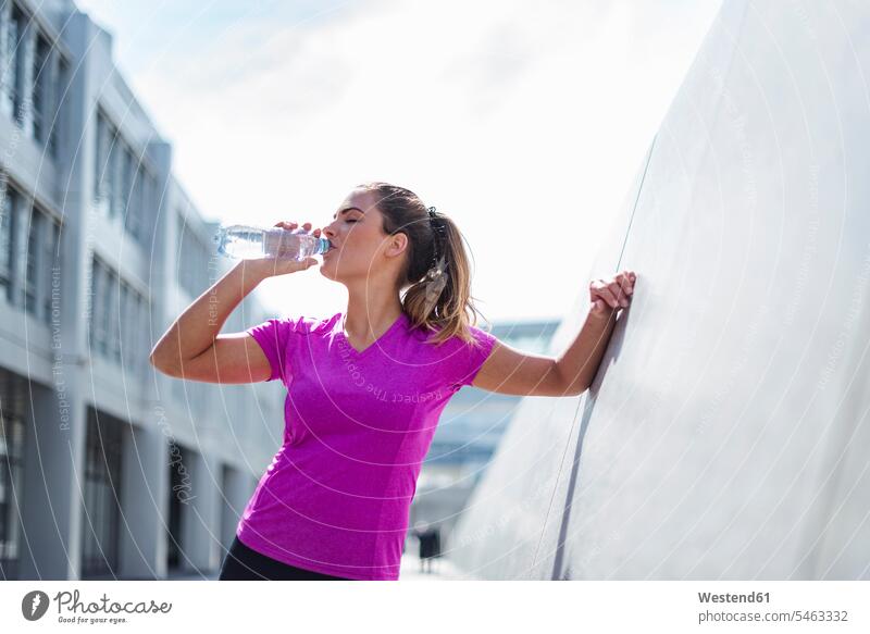 Young woman having a break from exercising drinking from bottle females women exercise training practising Bottle Bottles Adults grown-ups grownups adult people