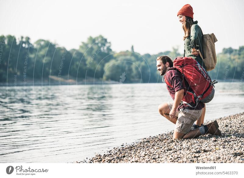 Smiling young couple with backpacks at the riverside rucksacks back-packs River Rivers twosomes partnership couples smiling smile riverbank water waters