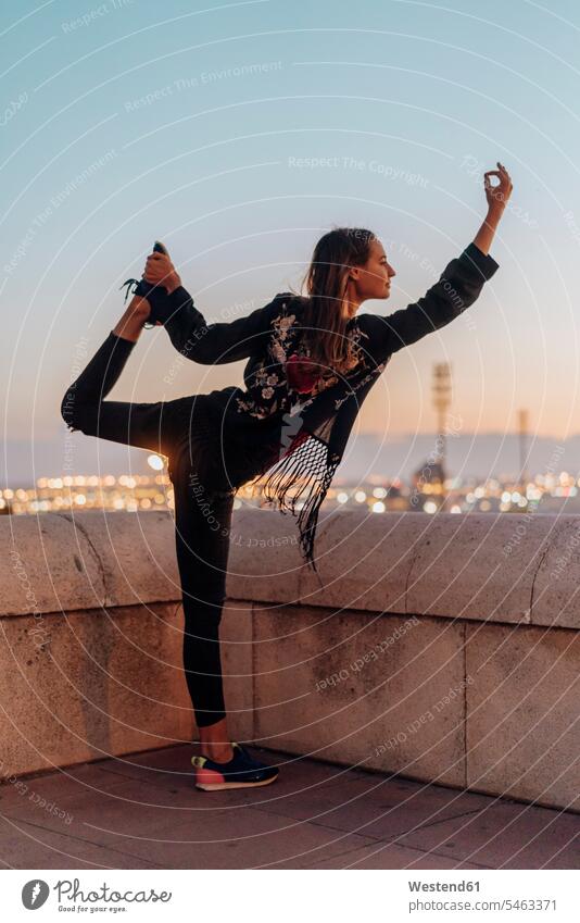 Spain, Barcelona, Montjuic, young woman doing yoga at dusk with city lights in background atmosphere atmospheric evening evening twilight females women Yoga