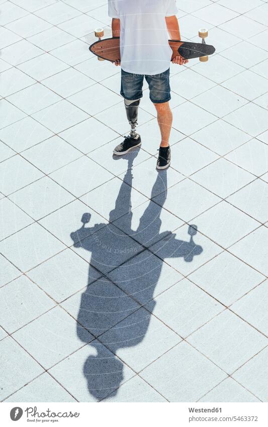 Young man with leg prosthesis holding skateboard T- Shirt t-shirts tee-shirt seasons summer time summertime summery stand sports athletes Sportsman Sportsmen