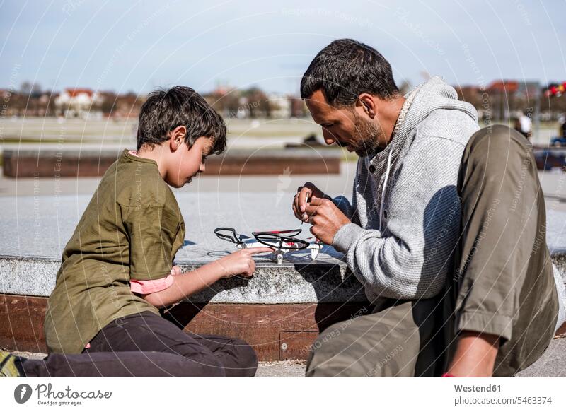 Father and son repairing drone drones sons manchild manchildren father fathers daddy dads papa family families people persons human being humans human beings