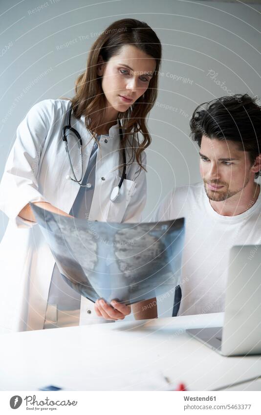 Two doctors with x-ray image at desk human human being human beings humans person persons caucasian appearance caucasian ethnicity european 2 2 people 2 persons