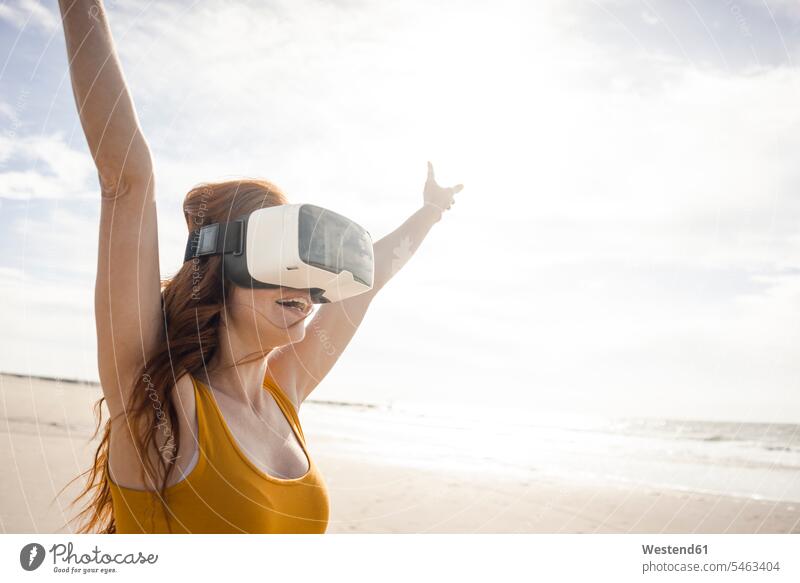 Redheaded woman using VR glasses on the beach beaches Virtual Reality Glasses Virtual-Reality Glasses virtual reality headset vr headset vr goggles