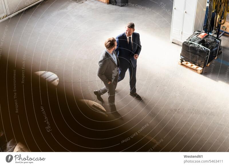 Bird's eye view of two businessmen walking and talking in a factory colleague Occupation Work job jobs profession professional occupation superior supervisor
