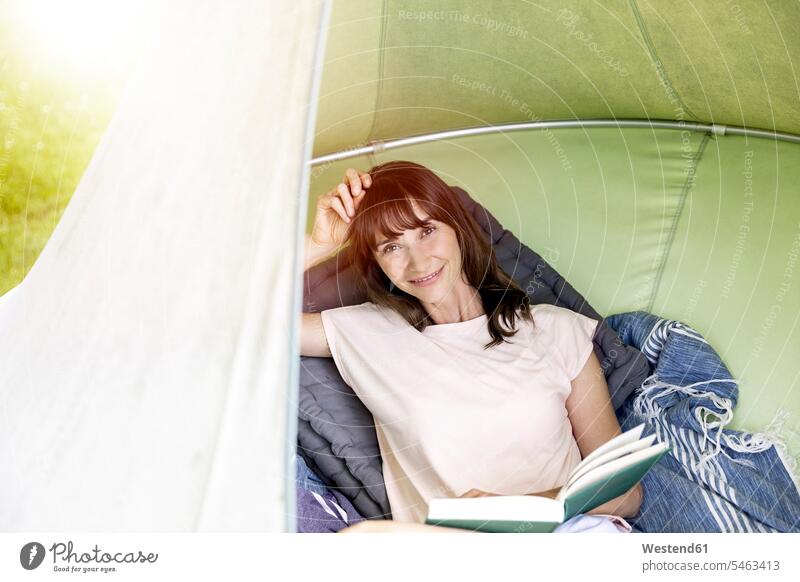 Portrait of smiling woman reading book in a hanging tent human human being human beings humans person persons caucasian appearance caucasian ethnicity european