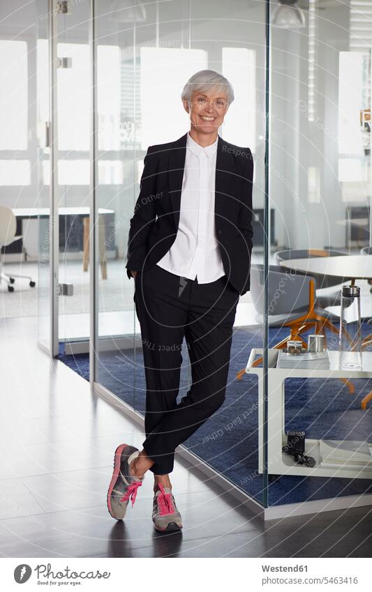Portrait of fashionable senior businesswoman wearing pantsuit and sneakers in office business life business world business person businesspeople business woman