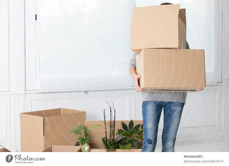 Unrecognizable woman carrying cardboard boxes in new home apartment flats apartments females women at home Cardboard Carton carton Cardboards cartons