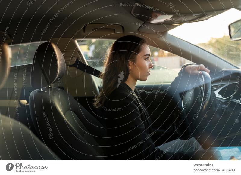 Young businesswoman looking away while driving car color image colour image Vehicle Interior sunset sunsets sundown atmosphere Idyllic atmospheric mood moody