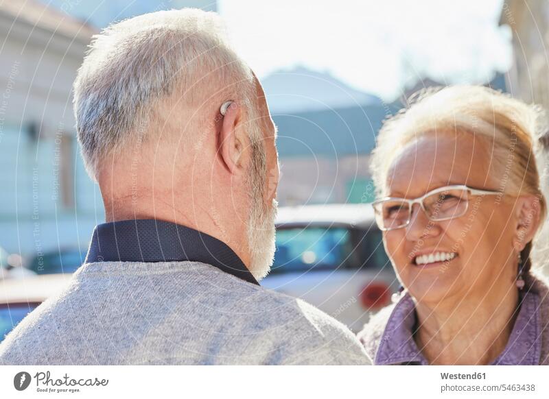 Close-up of senior man with hearing aid talking to senior woman senior women elder women elder woman old senior men elder man elder men senior citizen speaking