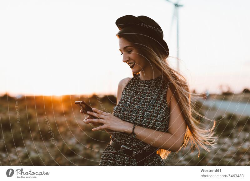 Portrait of young woman looking at cell phone by sunset portrait portraits sunsets sundown eyeing females women Smartphone iPhone Smartphones atmosphere