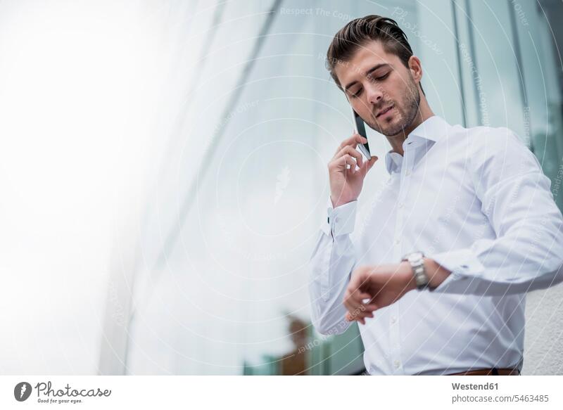 Businessman on cell phone checking the time wrist watch Wristwatch Wristwatches wrist watches Business man Businessmen Business men business people