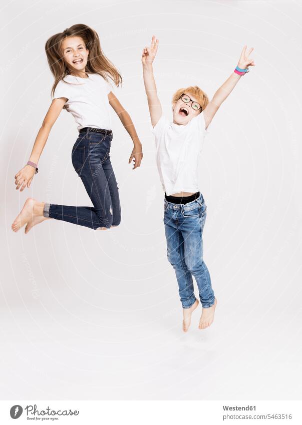 Cheerful siblings jumping against white background 12-13 years 12 to 13 years children kid kids people human being human beings humans persons 8-9 years