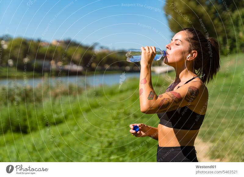 Sporty young woman having a cooling break at the riverside exercise practising train training hear drink seasons summer time summertime summery thirsty relax