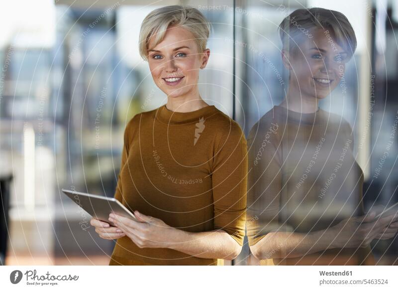 Portrait of smiling businesswoman with tablet at the window smile businesswomen business woman business women leaning windows portrait portraits digitizer