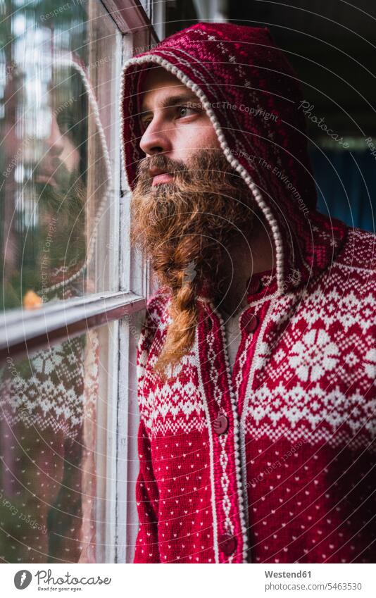 Portrait of pensive man with beard wearing hooded jacket looking out of window thoughtful Reflective contemplative view seeing viewing portrait portraits