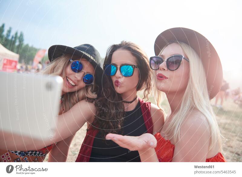 Happy friends making a video at music festival, puckering lips Selfie Selfies Smartphone iPhone Smartphones video film photographing pouting kiss peck pecks