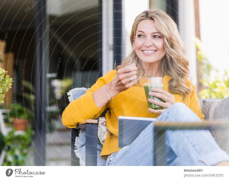 Portrait of smiling mature woman sitting on terrace with digital tablet enjoying green smoothie Crockery Tableware Drinking Glass Drinking Glasses jumper