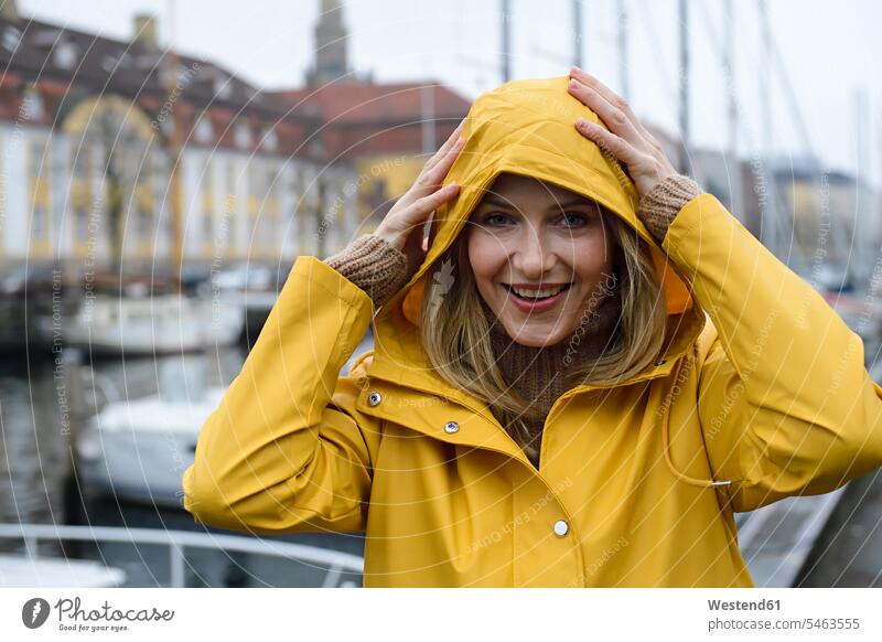 Denmark, Copenhagen, portrait of happy woman at city harbour in rainy weather females women happiness town cities towns portraits Adults grown-ups grownups
