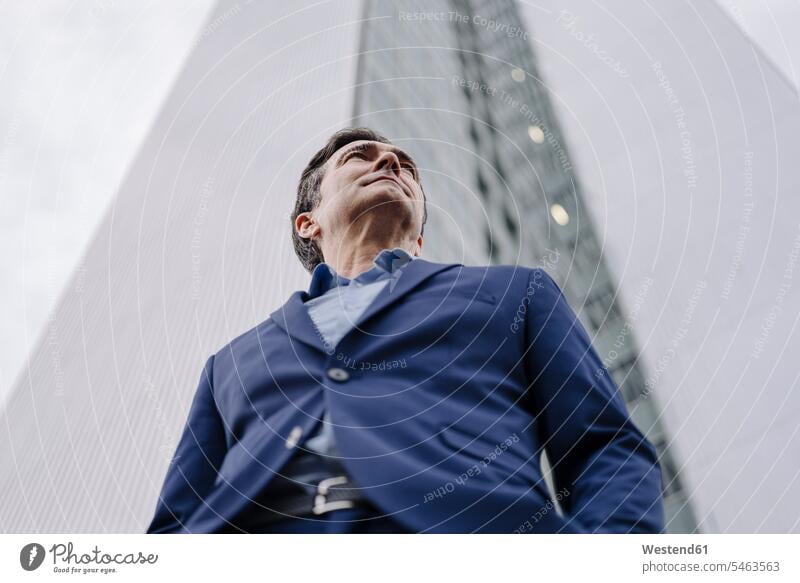 Confident mature businessman standing in front of an office tower in the city human human being human beings humans person persons caucasian appearance