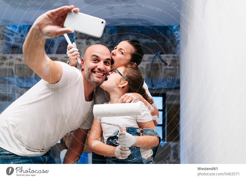 Happy family taking a selfie while painting the walls of her new house T- Shirt t-shirts tee-shirt telecommunication phones telephone telephones cell phone
