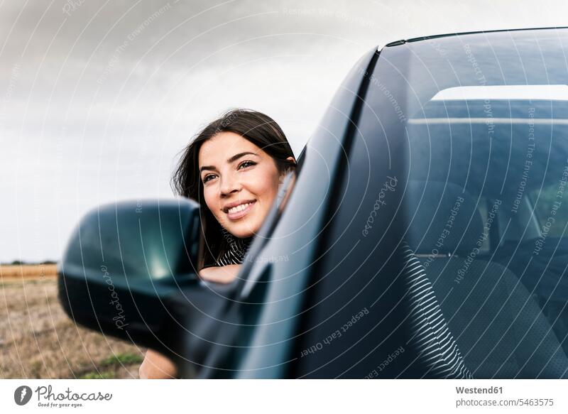 Smiling young woman leaning out of car window windows automobile Auto cars motorcars Automobiles smiling smile females women happiness happy motor vehicle