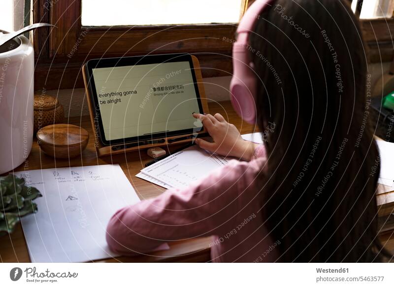 Girl wearing headphones translating languages on digital tablet while learning comics at home color image colour image indoors indoor shot indoor shots interior