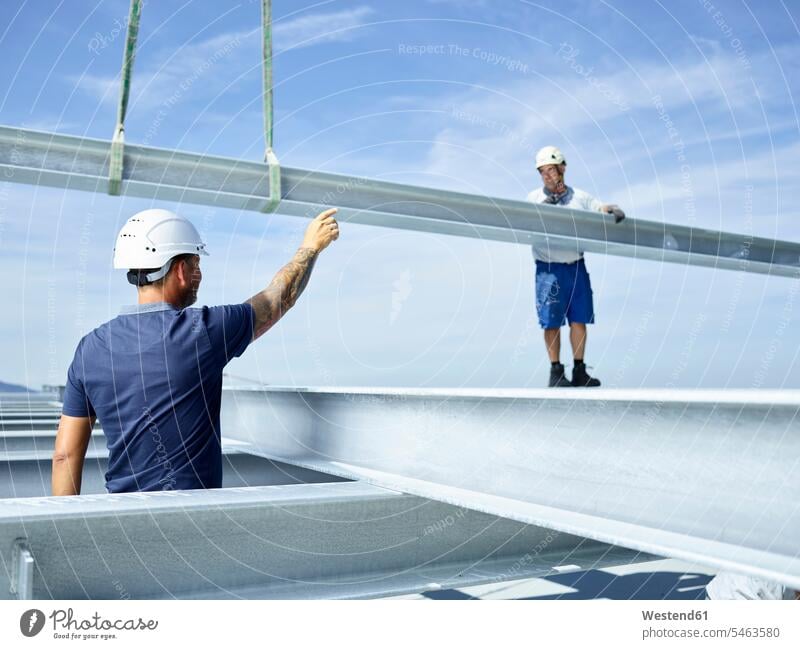Worker on construction site standing on steel girder, getting instructions from lead worker working At Work Building Site sites Building Sites