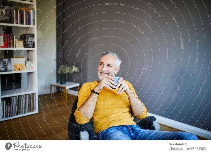 Smiling relaxed mature man at home with cup of coffee human human being human beings humans person persons celibate celibates singles solitary people
