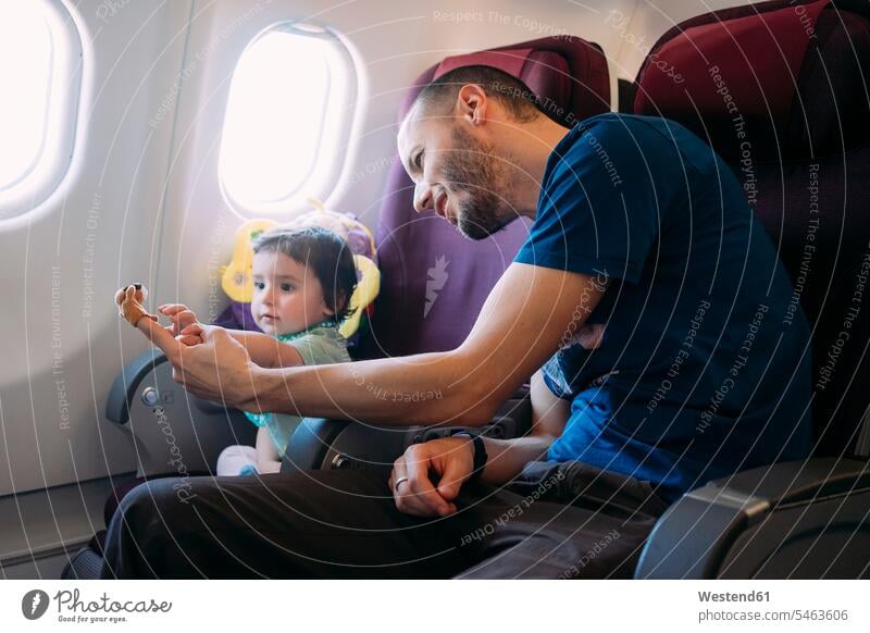 Father playing with his little daughter on airplane father pa fathers daddy papa journey travelling Journeys voyage air travel air travelling flight flights