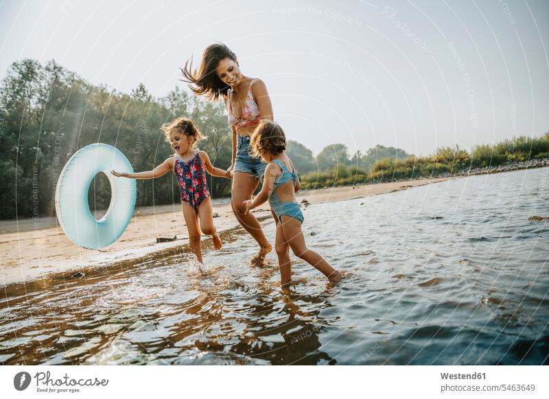 Mother and daughters walking at the river, holding hands color image colour image outdoors location shots outdoor shot outdoor shots day daylight shot
