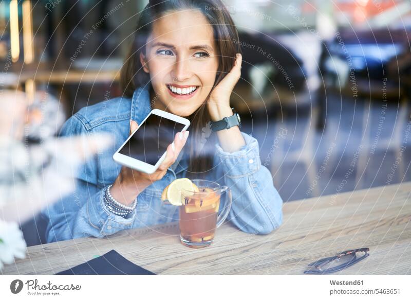 Smiling young woman speaking on phone in cafe while having tea smiling smile Tea Teas on the phone call telephoning On The Telephone calling mobile phone