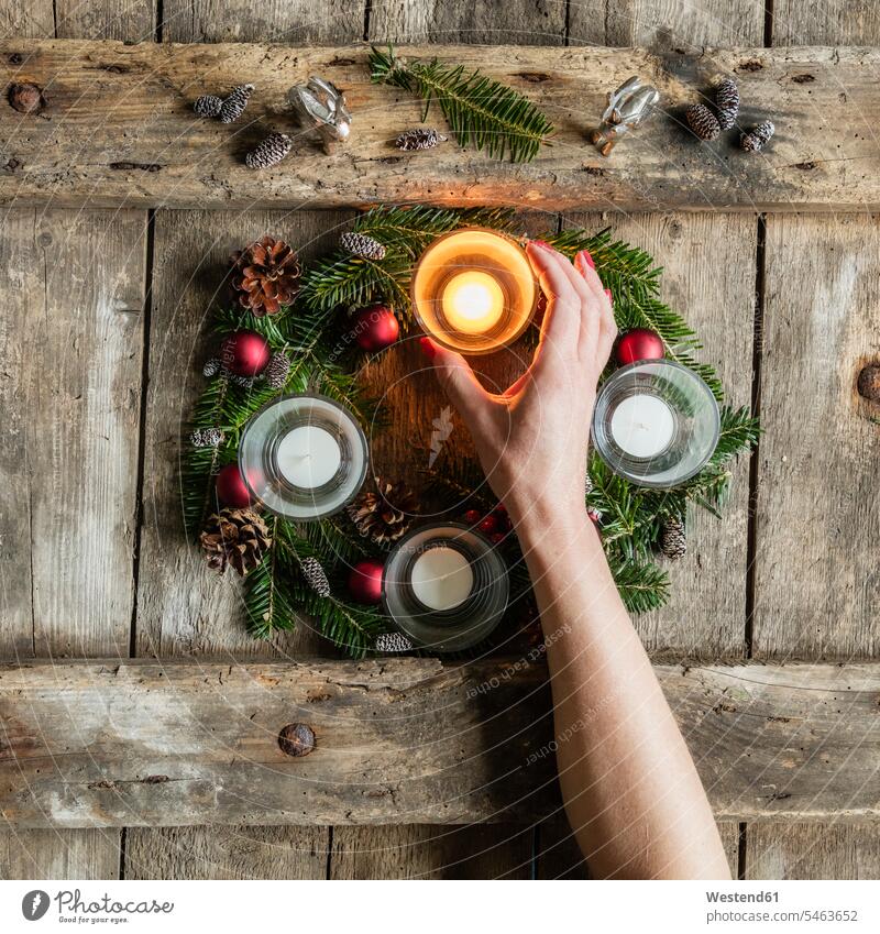 Hand of woman touching glass cover of candle burning on Advent wreath indoors indoor shot indoor shots interior interior view Interiors overhead view