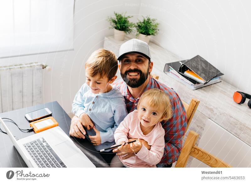 Father working at home, using laptop with his children on his lap daughter daughters father pa fathers daddy dads papa laughing Laughter At Work son sons
