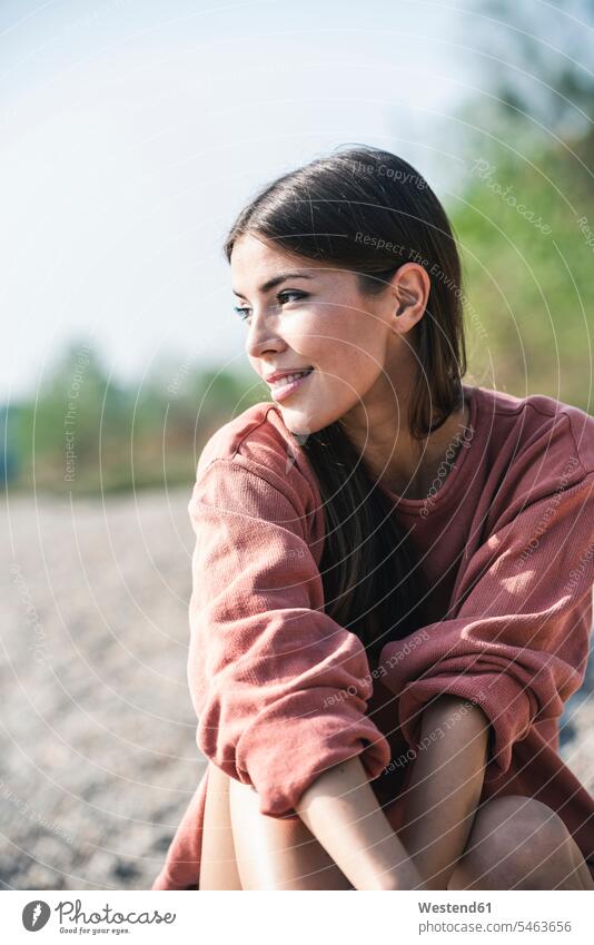 Smiling young woman sitting outdoors portrait portraits smiling smile Seated females women Adults grown-ups grownups adult people persons human being humans