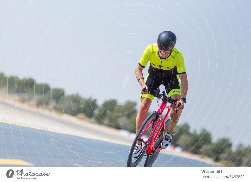 Determined cyclist riding bicycle on road against clear sky, Dubai, United Arab Emirates color image colour image outdoors location shots outdoor shot