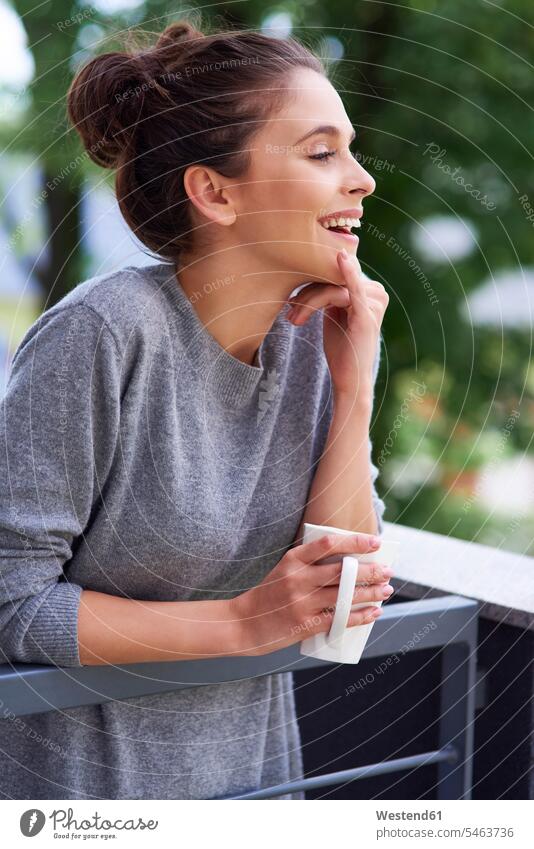 Young woman drinking morning coffee on the balcony Coffee standing balconies laughing Laughter young women young woman in the morning Drink beverages Drinks