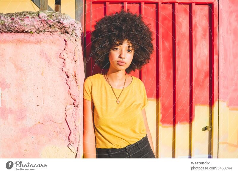 Portrait of young woman with afro hairdo leaning against a wall human human being human beings humans person persons curl curled curls curly hair T- Shirt