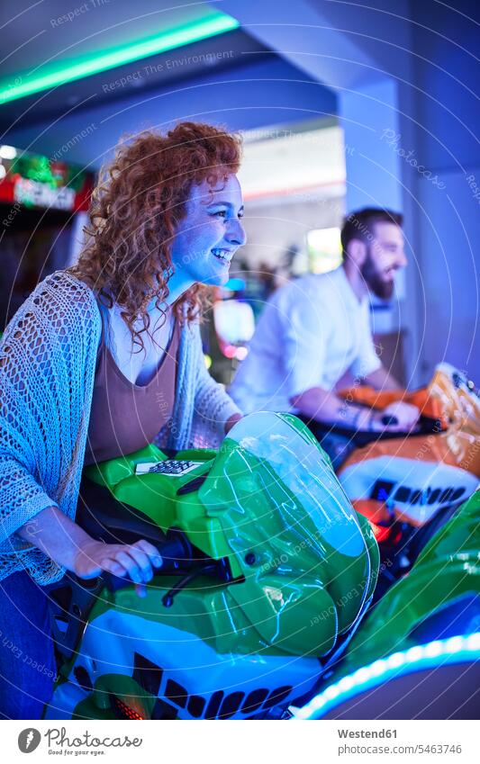 Woman playing and having fun with a driving simulator in an amusement arcade human human being human beings humans person persons curl curled curls curly hair
