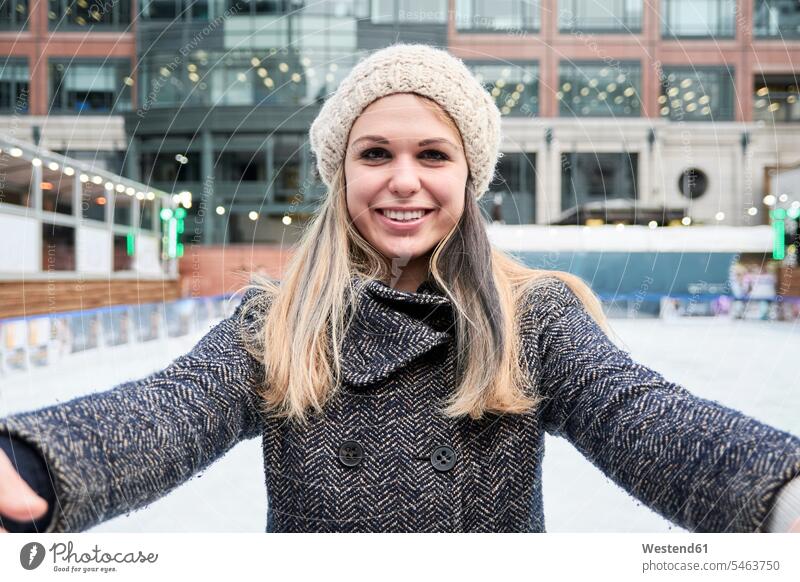 Blond young woman looking at the camera while skiing on an ice rink wearing laughing Laughter females women winter hibernal Fun having fun funny ice skating