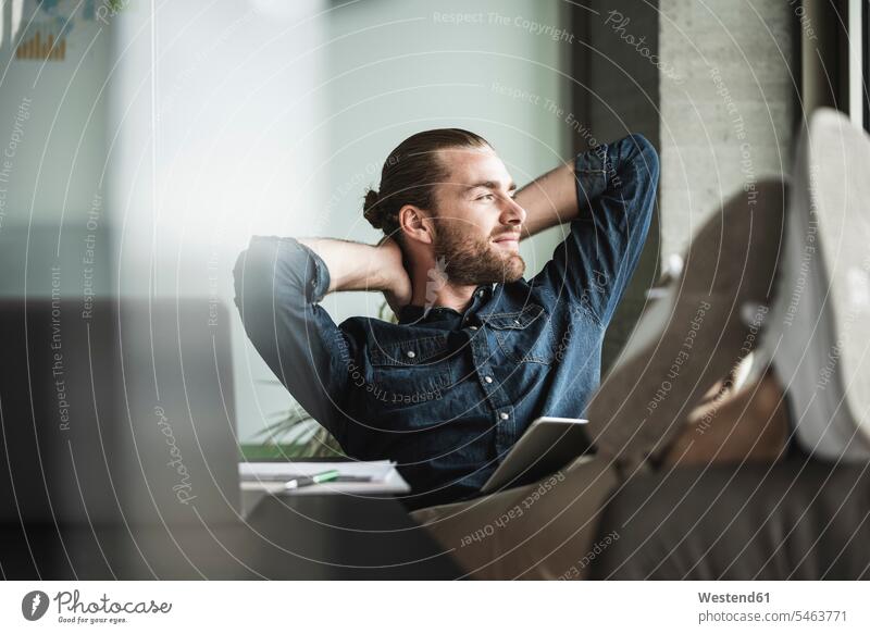 Relaxed smiling businessman sitting in office looking out of window relaxed relaxation smile Seated Businessman Business man Businessmen Business men offices