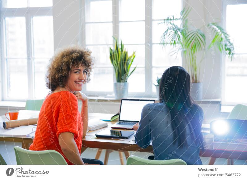Smiling woman with colleague in modern office with video projector on table human human being human beings humans person persons caucasian appearance