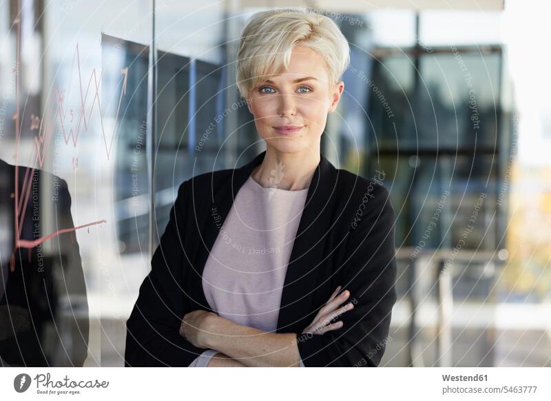 Portrait of confident businesswoman next to chart on glass pane in office glass panes businesswomen business woman business women offices office room