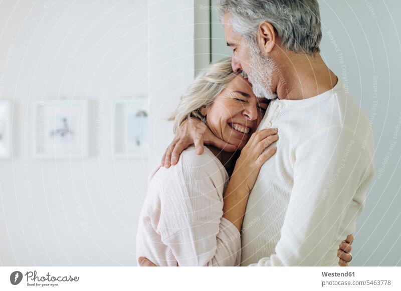 Affectionate mature couple hugging at home smile embrace Embracement relax relaxing relaxation delight enjoyment Pleasant pleasure Cheerfulness exhilaration