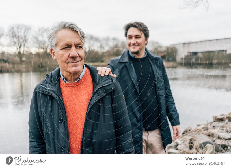 Confident senior man and young man standing at the riverside riverbank confidence confident men males water's edge waterside shore Adults grown-ups grownups