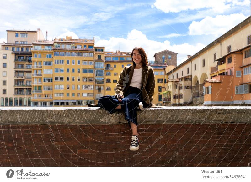 Italy, Florence, smiling young woman resting on a wall in the city residential house Residential Buildings residential home portrait portraits positive content
