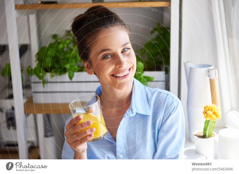 Young woman drinking orange juice in her kitchen Glass Drinking Glasses portrait portraits looking at camera looking to camera looking at the camera Eye Contact