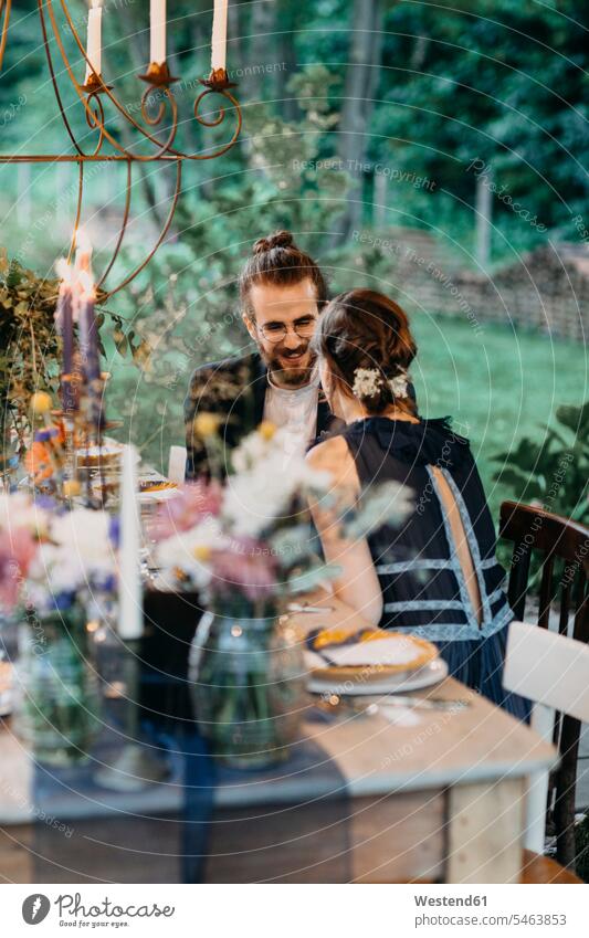 Happy bride and groom sitting at festive laid table outdoors Seated brides Table Tables happiness happy bridal couple bridal couples bridegrooms Wedding