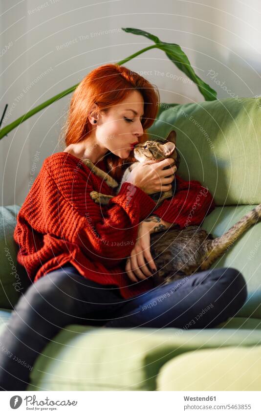 Red-haired woman with cat on couch at home human human being human beings humans person persons caucasian appearance caucasian ethnicity european 1